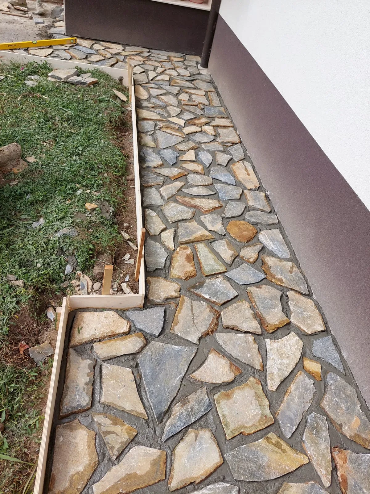 Alee perimetrală din piatră naturală realizată lângă casă.