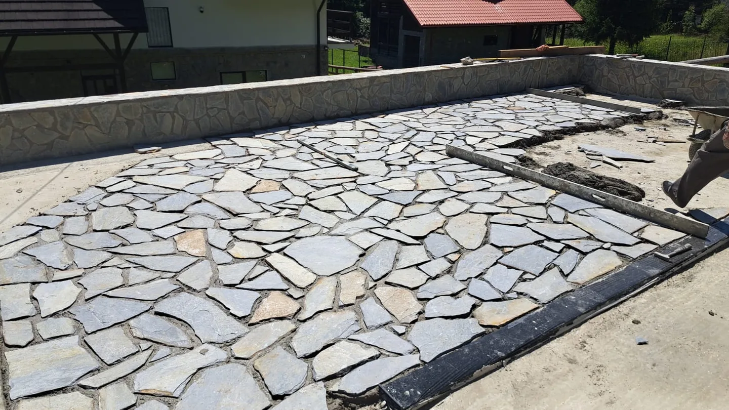 Suprafață exterioară în curs de amenajare cu piatră naturală.