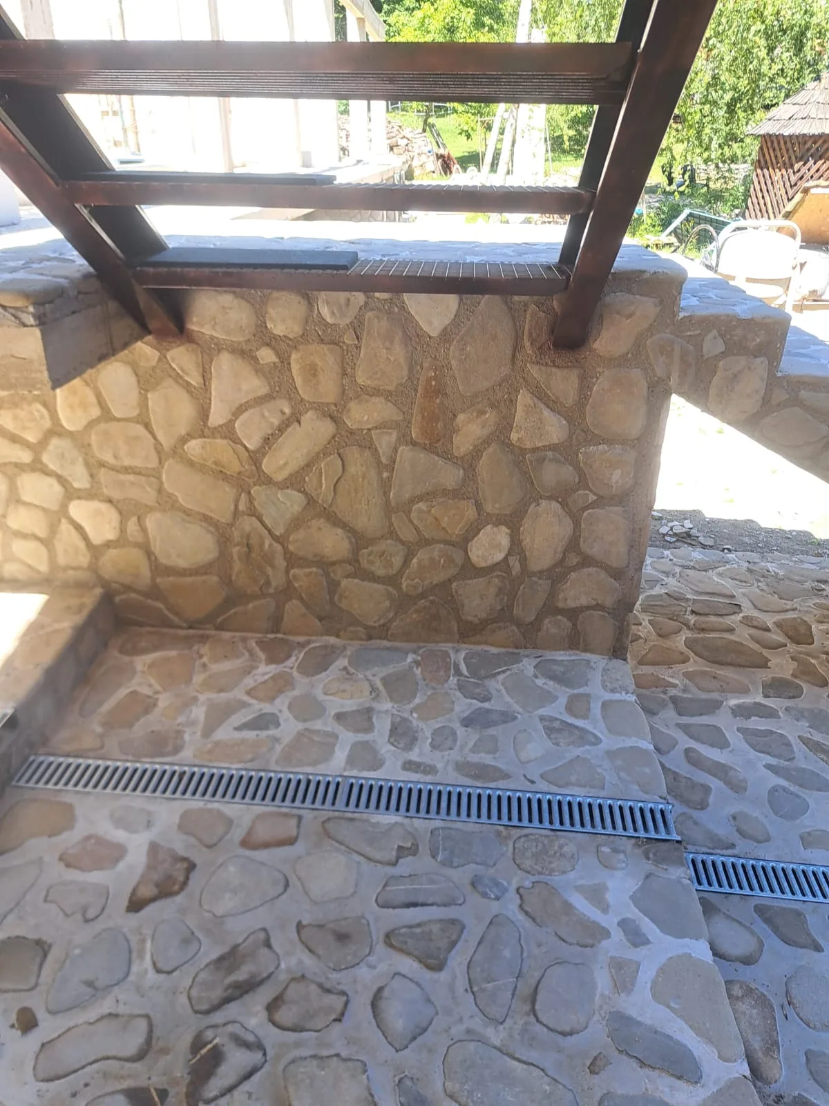 Pardoseală și banchetă exterioară placate cu piatră naturală.