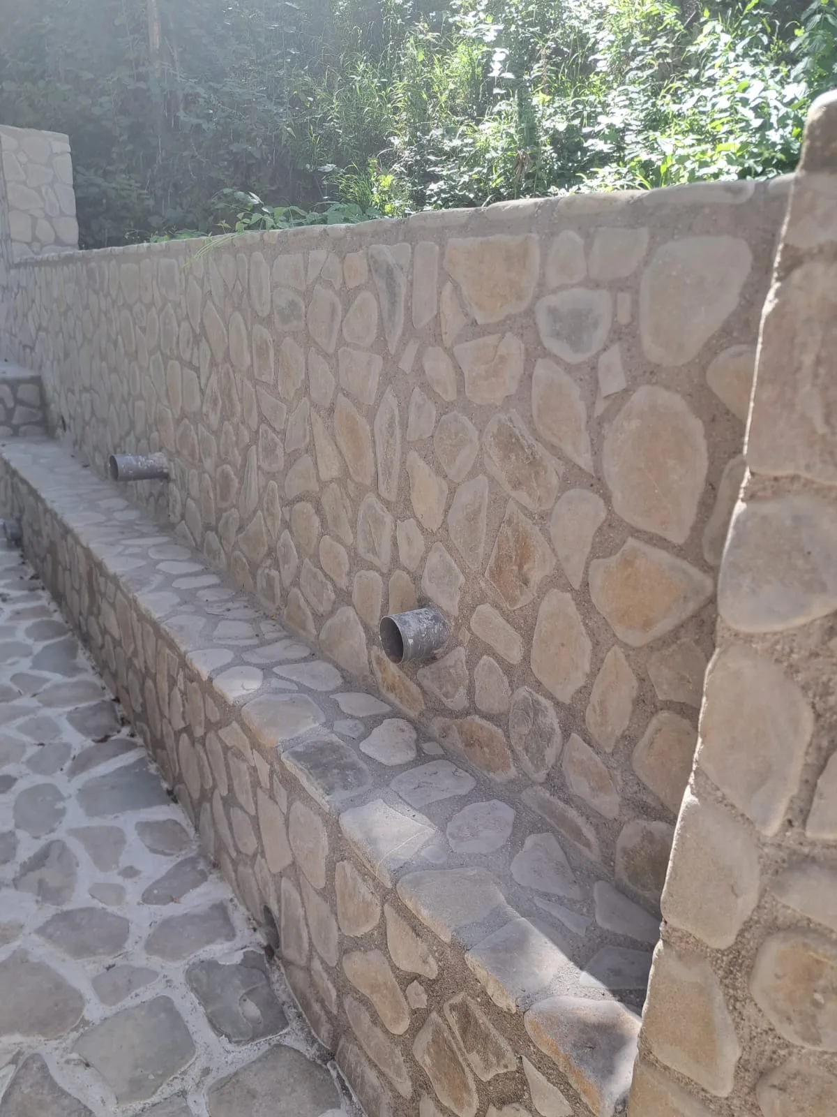 Zid exterior și banchetă finisate cu piatră naturală.